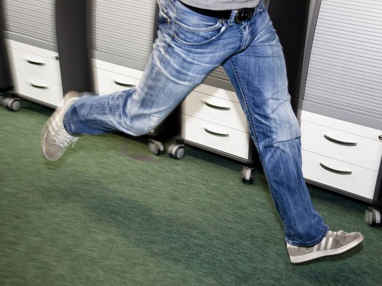 Close-up of a running man in the office corridor