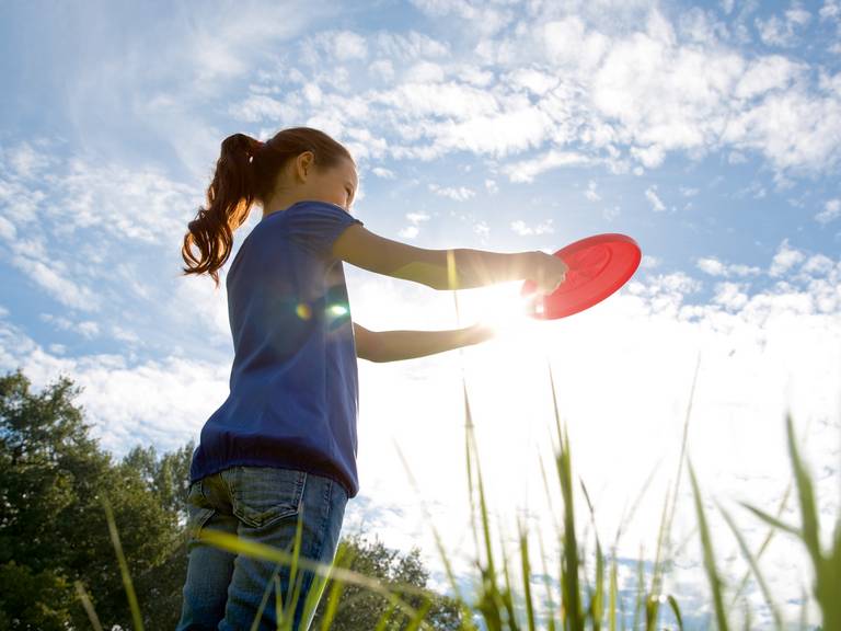 Young girl holds a red Frisbee in her hand