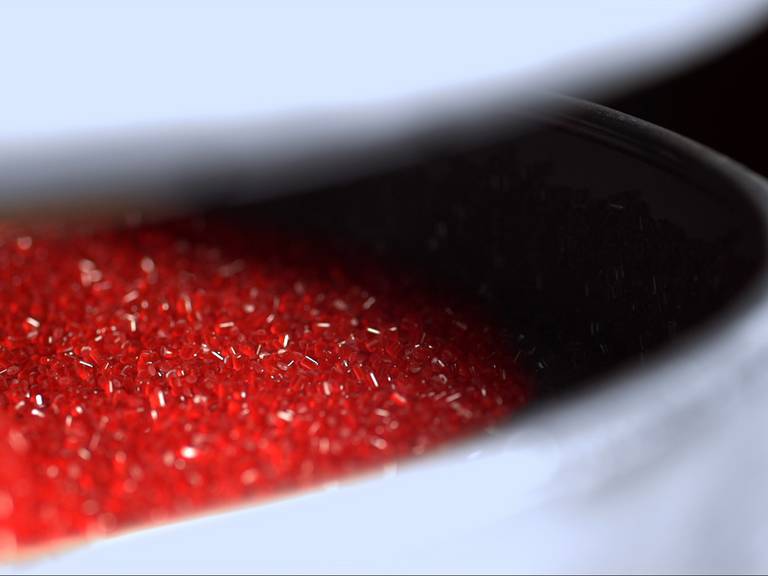 Material view of red plastic pellets in a machine
