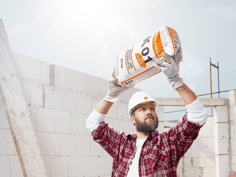Construction worker lifts a bag of cement in a building site